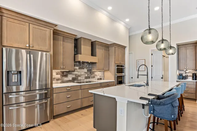 a kitchen with stainless steel appliances kitchen island granite countertop a table chairs sink and cabinets
