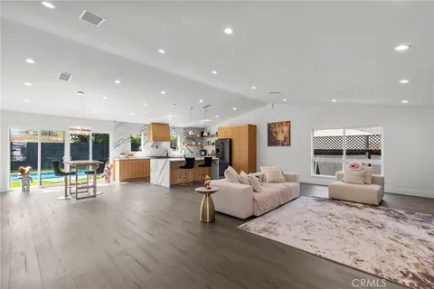 a living room with furniture and kitchen view with wooden floor