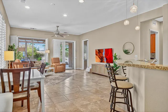 a living room with furniture a rug potted plant and a large window
