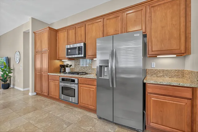 a kitchen with granite countertop a refrigerator stove and cabinets