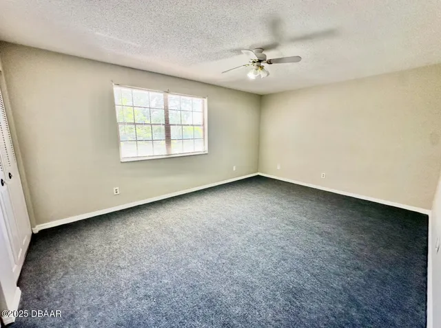an empty room with a ceiling fan and window