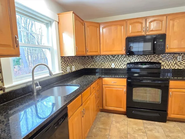 a kitchen with granite countertop a stove a sink and a microwave