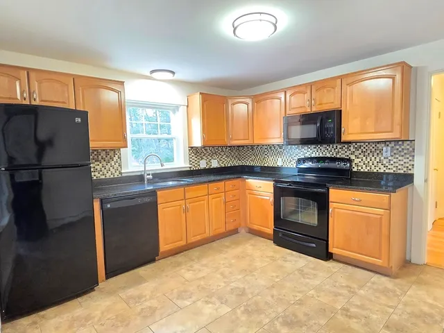 a kitchen with granite countertop a stove a sink and a refrigerator
