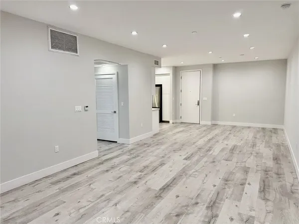 an empty room with wooden floor and mirror