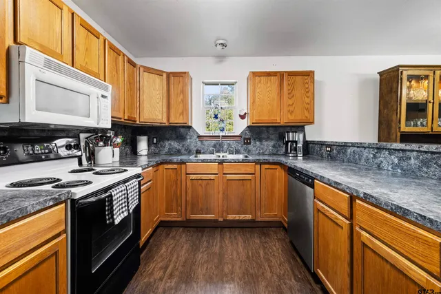 a kitchen with stainless steel appliances granite countertop wooden cabinets a stove a sink and a microwave