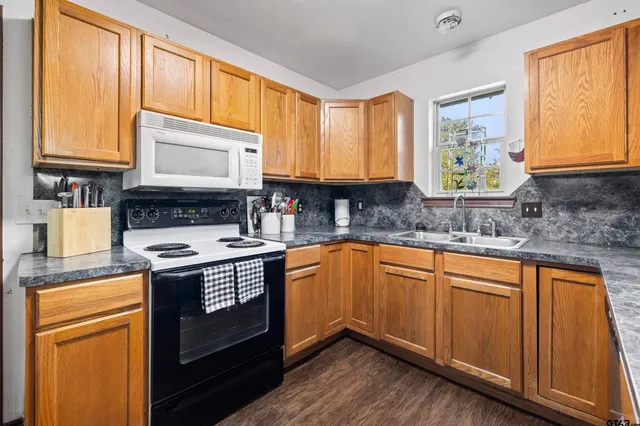 a kitchen with stainless steel appliances granite countertop wooden cabinets a stove a sink and a window