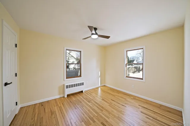 a view of an empty room with a window and wooden floor