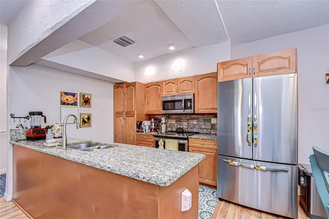 a kitchen with stainless steel appliances granite countertop a refrigerator and a stove top oven