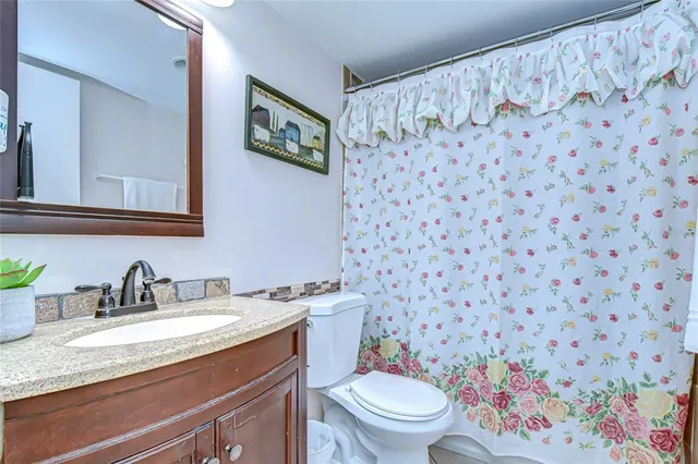a bathroom with a granite countertop sink and a toilet
