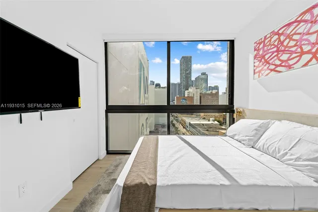 a bedroom with a bed and a flat tv screen next to a window