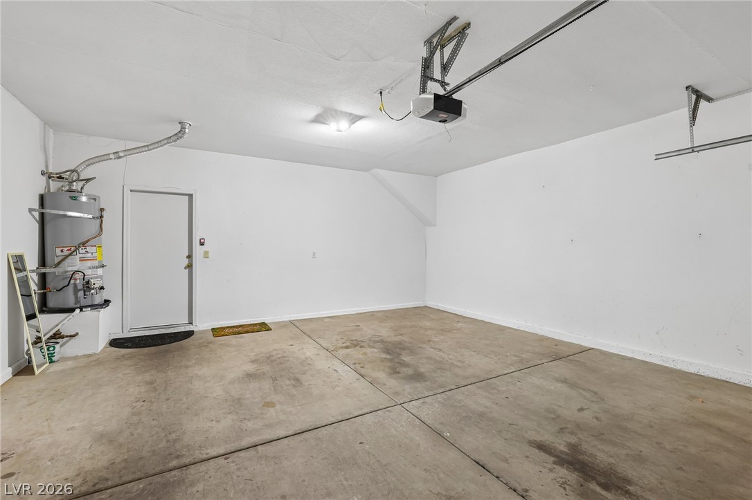 1727 Millstream Way Henderson, NV 89074 - Photo 42 of 46 A spacious, well-lit garage with a clean concrete floor, offering ample room for parking and storage.