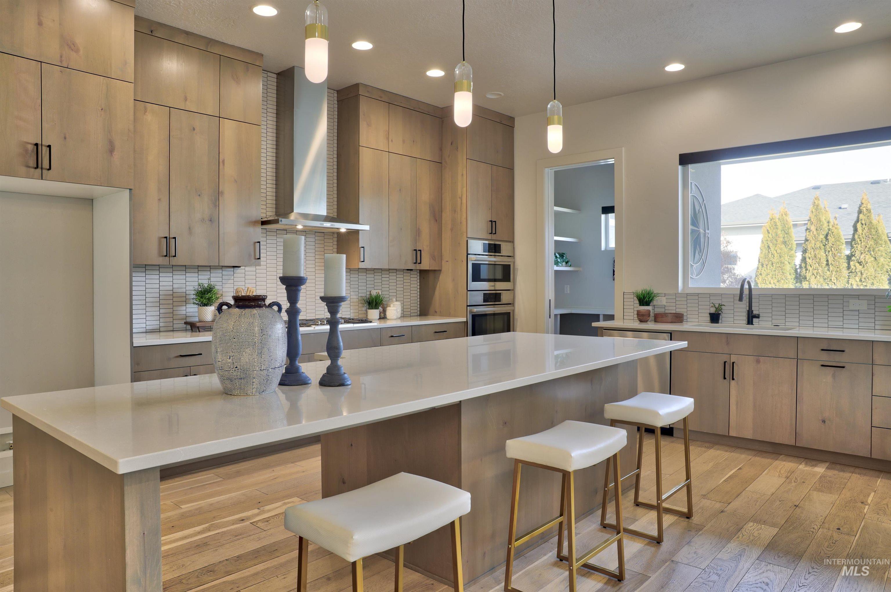 4148 East Copper Point Drive Meridian, ID 83642 - Photo 7 of 26 Kitchen with light wood-style flooring, pendant lighting, light stone counters, and tasteful backsplash