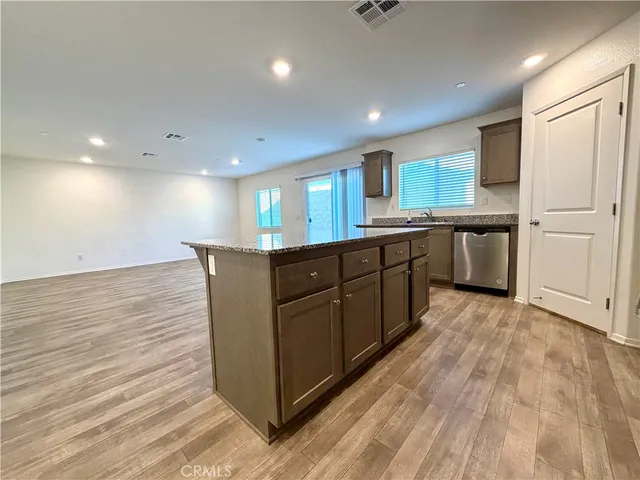 a large kitchen with stainless steel appliances granite countertop a large counter top and wooden floors