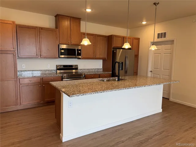 a kitchen with stainless steel appliances granite countertop a sink a stove and a wooden floors