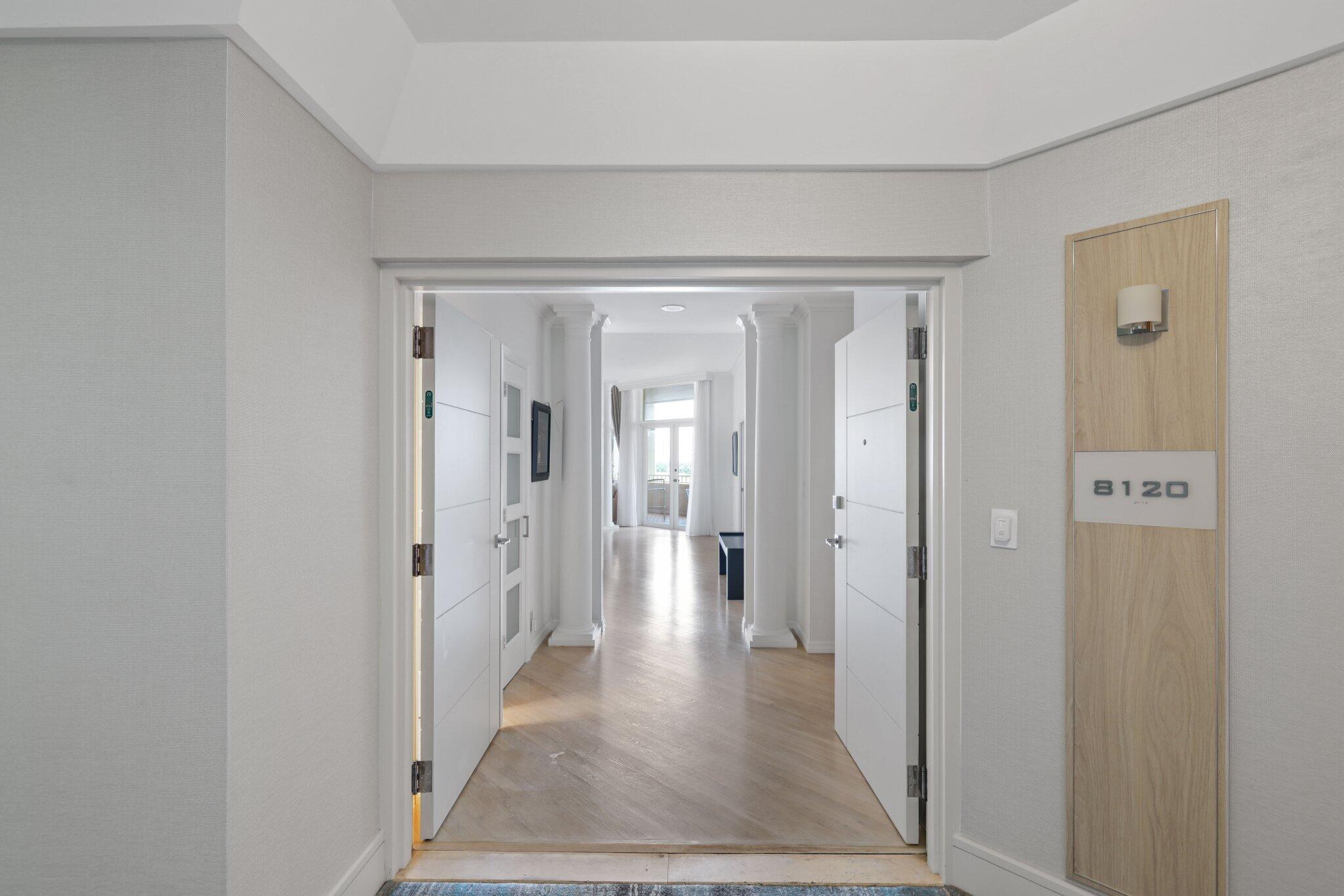 a view of a hallway with wooden floor and a living room