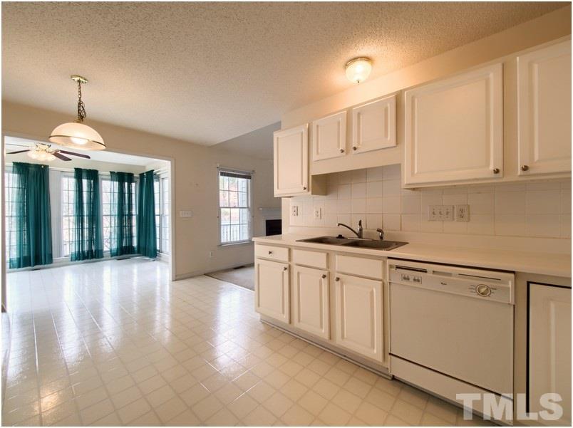 9513 Cub Trail Raleigh, NC 27615 - Photo 5 of 8 a kitchen with granite countertop white cabinets and white appliances