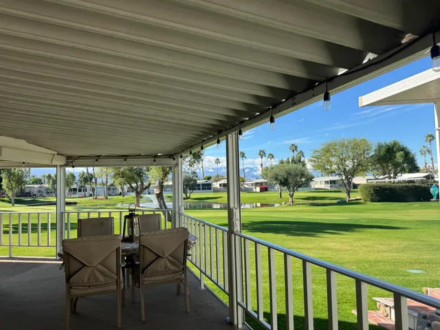 a view of a patio with chairs and floor to ceiling window with garden