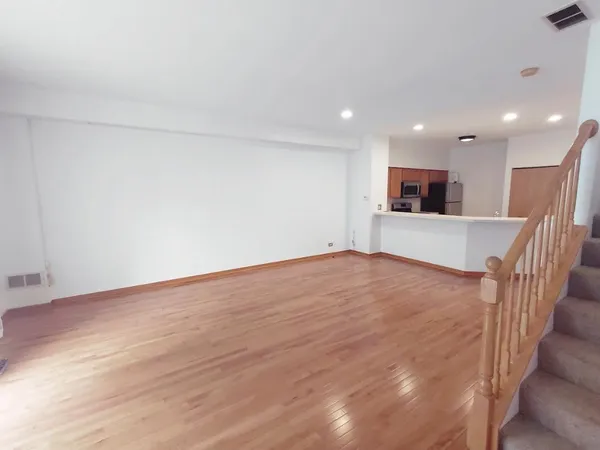 a view of an empty room with wooden floor and stairs