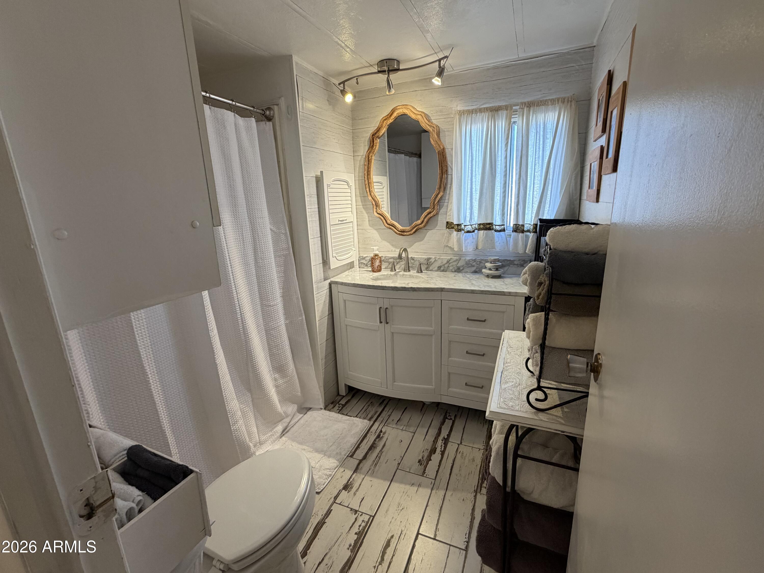 3104 East Broadway Road North, Unit 307 Mesa, AZ 85204 - Photo 10 of 11 a bathroom with a sink a mirror a toilet and a window