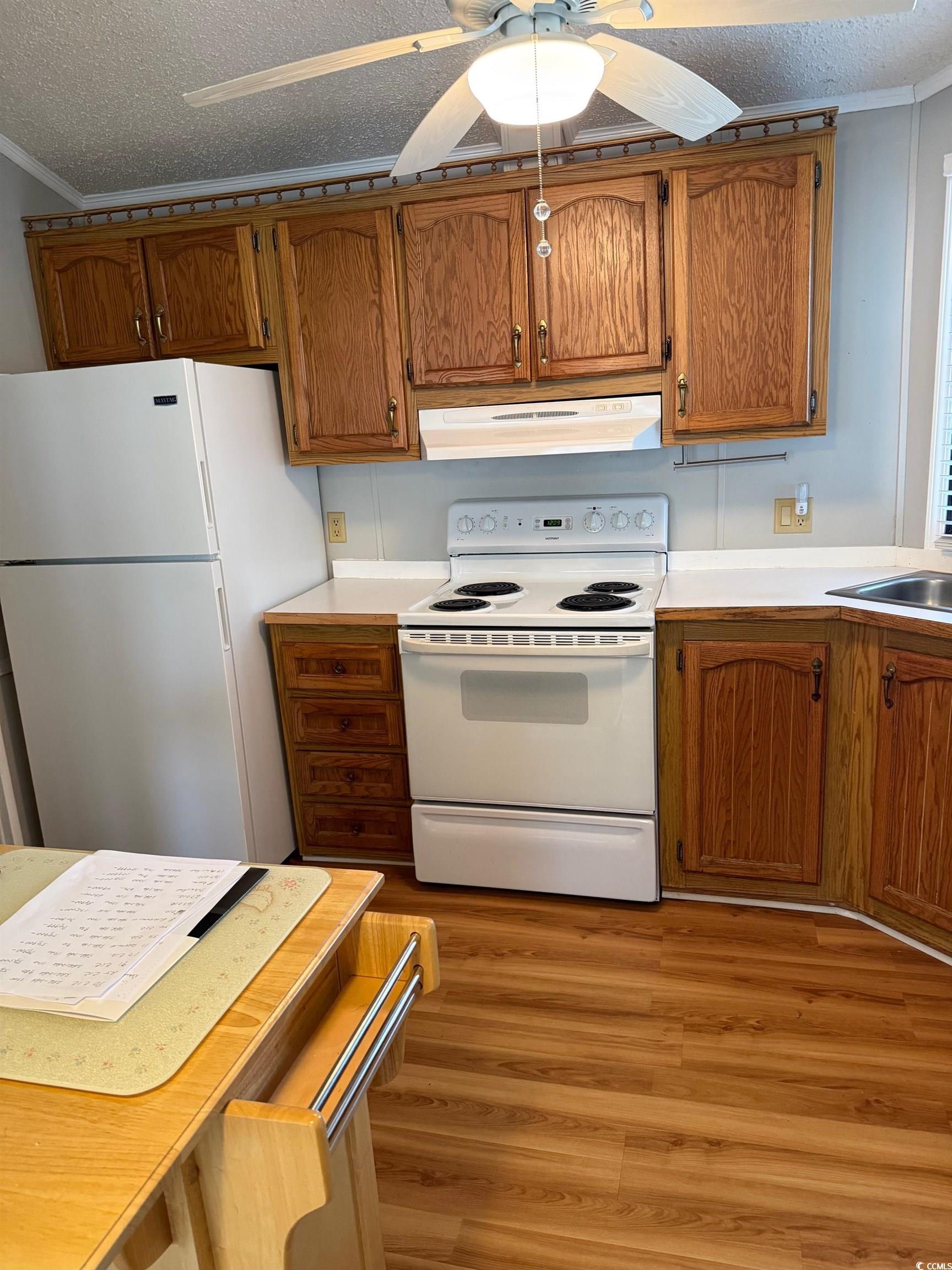 159 Crooked Island Circle Murrells Inlet, SC 29576 - Photo 5 of 20 Kitchen featuring white appliances, light countertops, a textured ceiling, brown cabinets, and ornamental molding