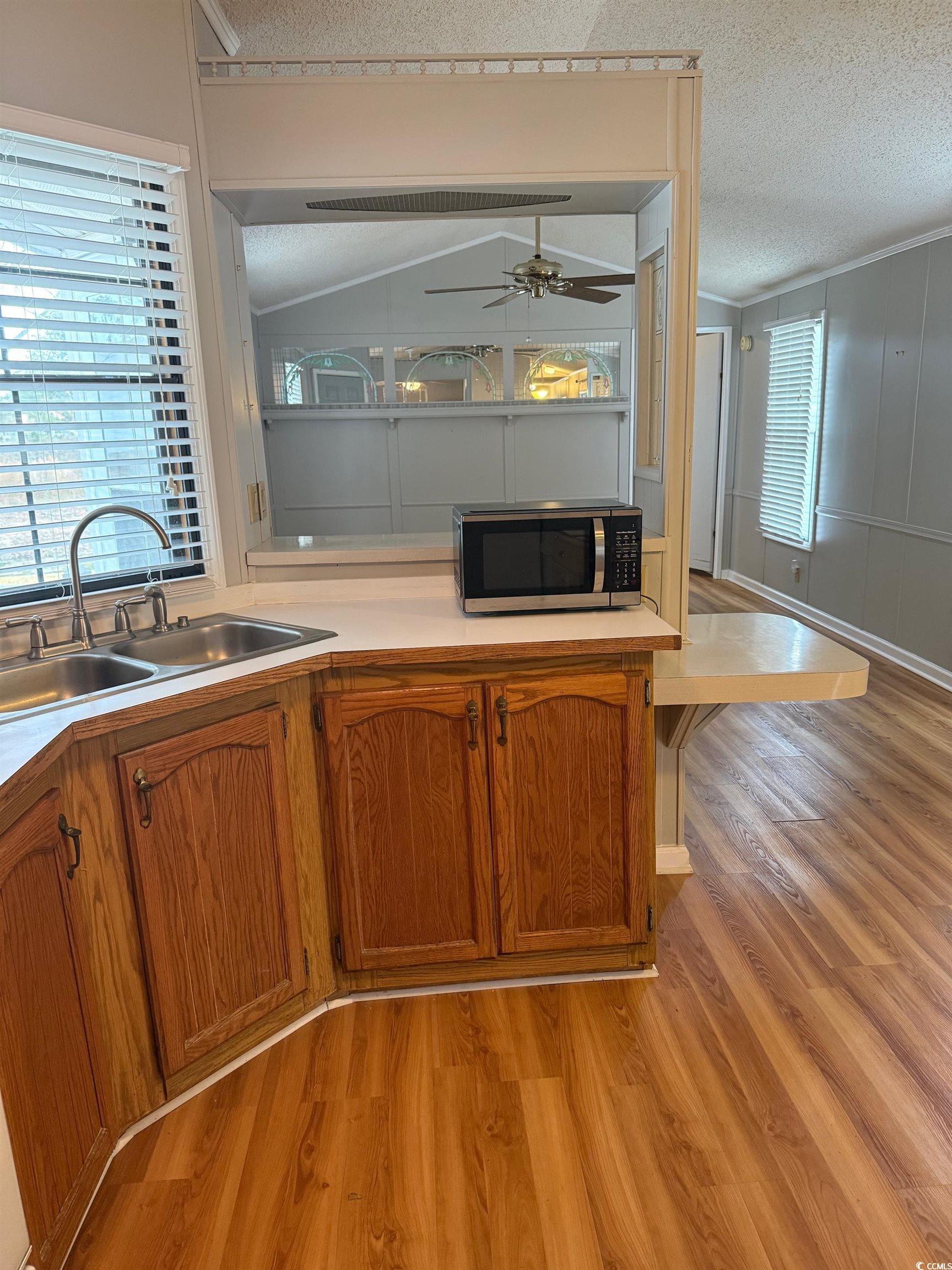 159 Crooked Island Circle Murrells Inlet, SC 29576 - Photo 7 of 20 Kitchen featuring light wood-style flooring, light countertops, brown cabinetry, stainless steel microwave, and ceiling fan