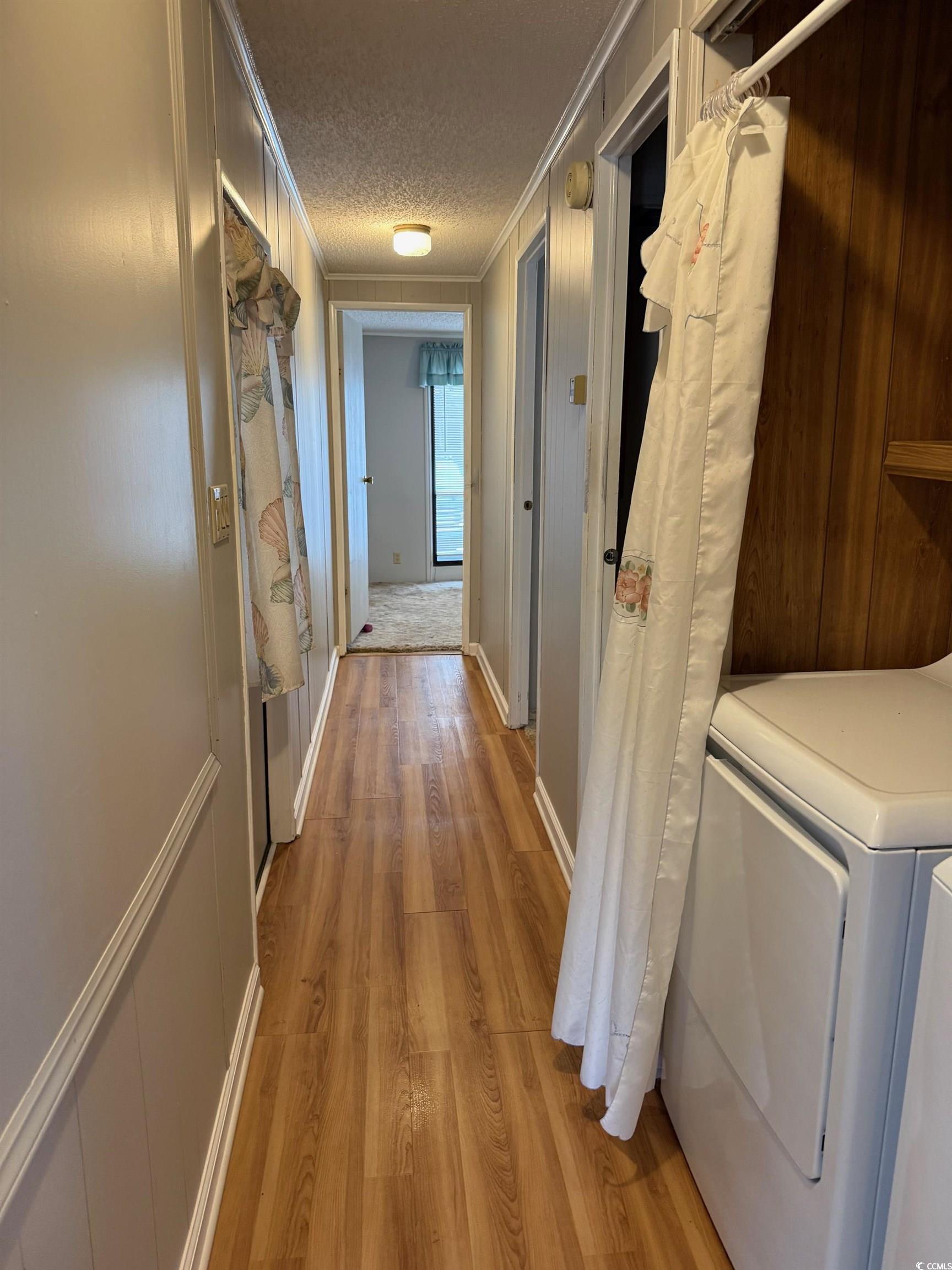 159 Crooked Island Circle Murrells Inlet, SC 29576 - Photo 10 of 20 Hallway with ornamental molding, light wood-style flooring, a textured ceiling, a decorative wall, and independent washer and dryer