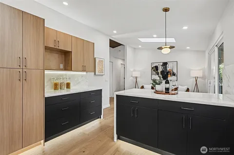 a kitchen with stainless steel appliances granite countertop a stove top oven a sink a dining table and chairs with wooden floor