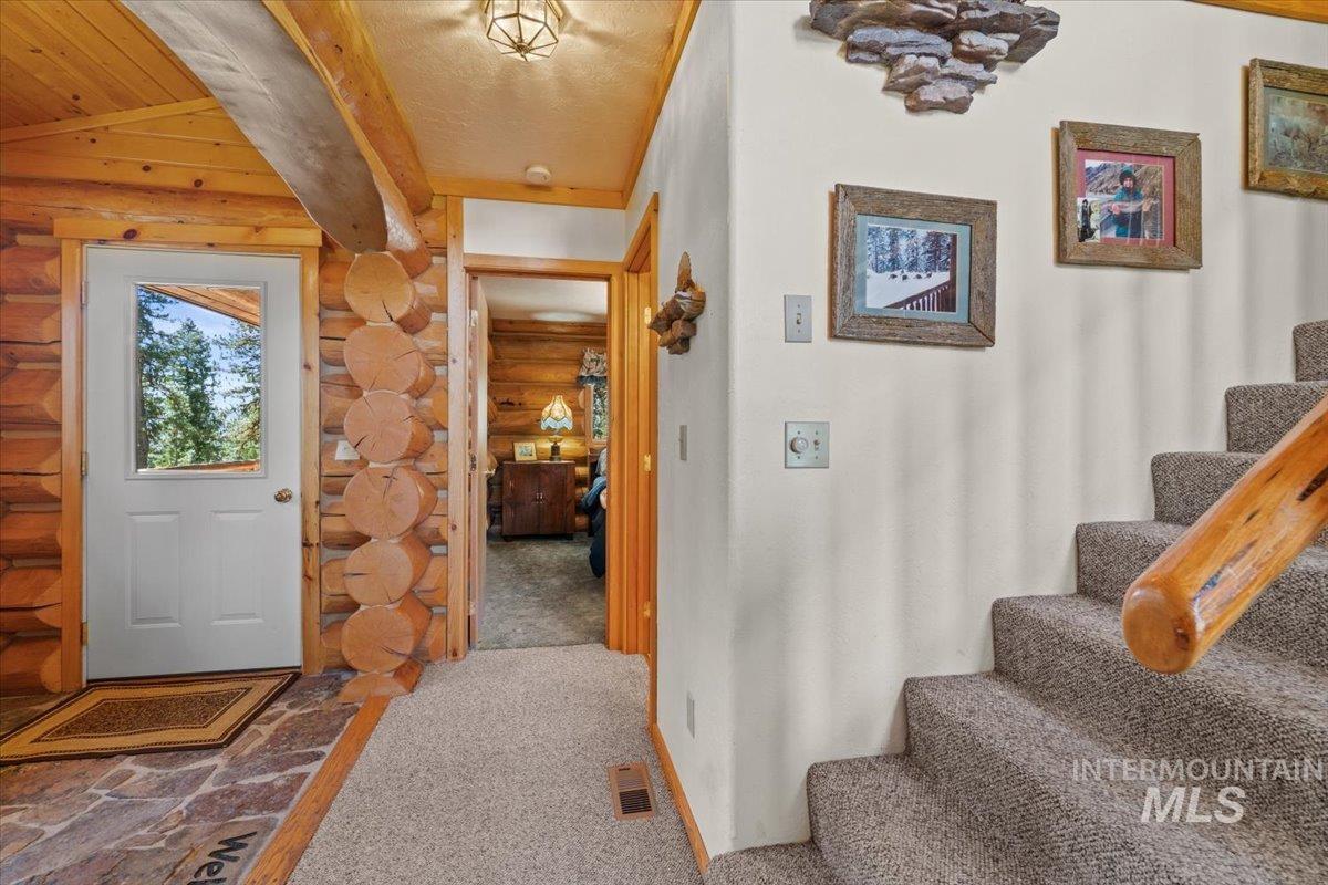 3725 Rim Road New Meadows, ID 83654 - Photo 13 of 50 Entryway with stairway, carpet floors, log walls, beamed ceiling, and a textured ceiling