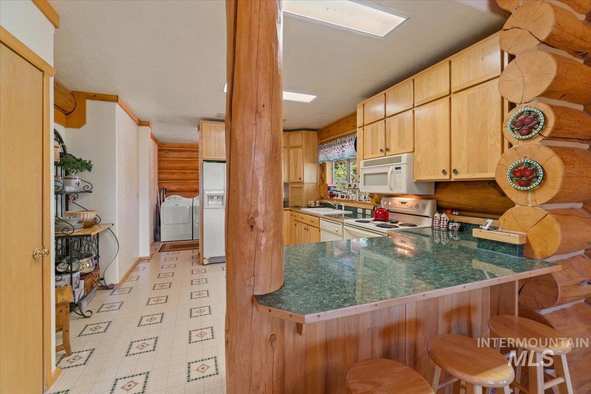 3725 Rim Road New Meadows, ID 83654 - Photo 16 of 50 Kitchen with light brown cabinets, white appliances, light flooring, and a peninsula