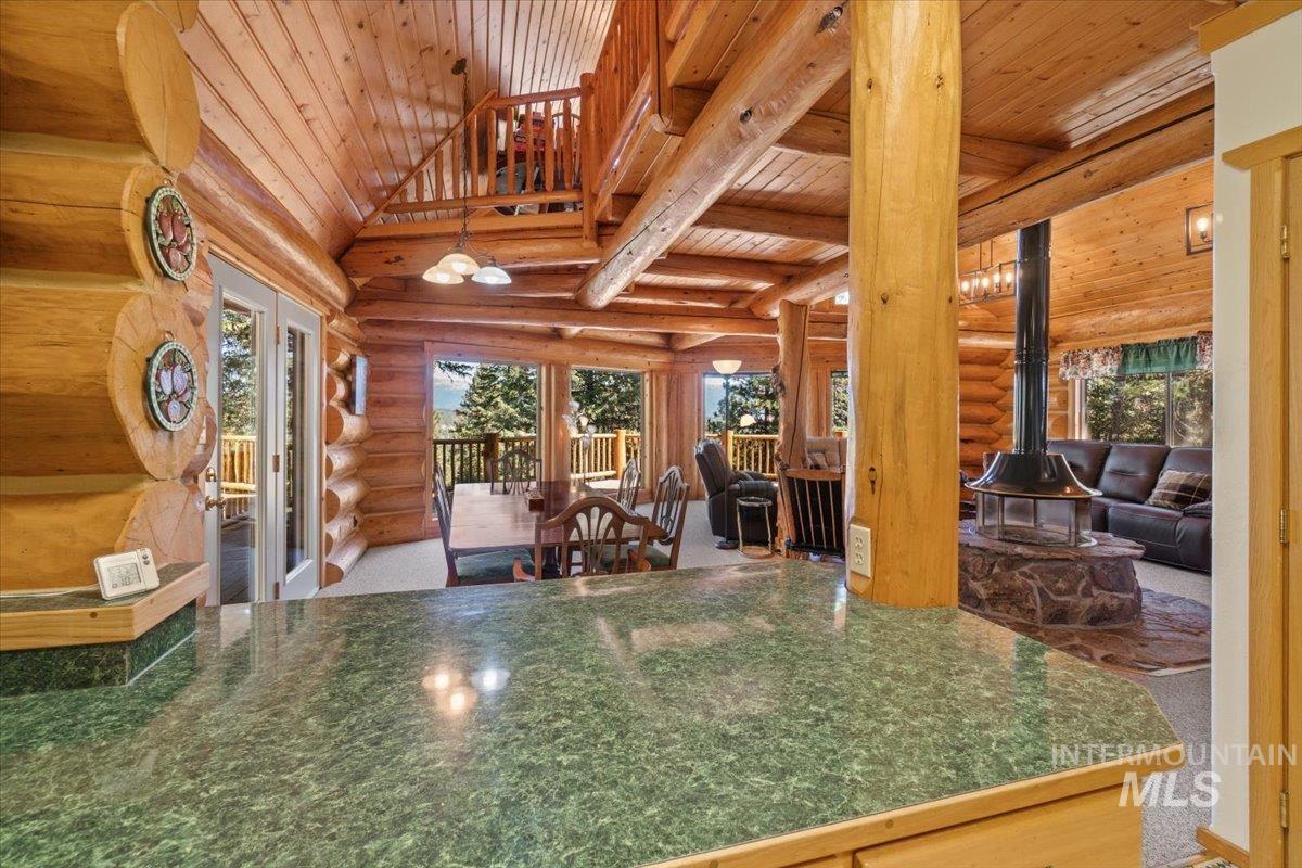 3725 Rim Road New Meadows, ID 83654 - Photo 19 of 50 Kitchen featuring rustic walls, a wood stove, a wood ceiling with exposed beams, dark countertops, and french doors