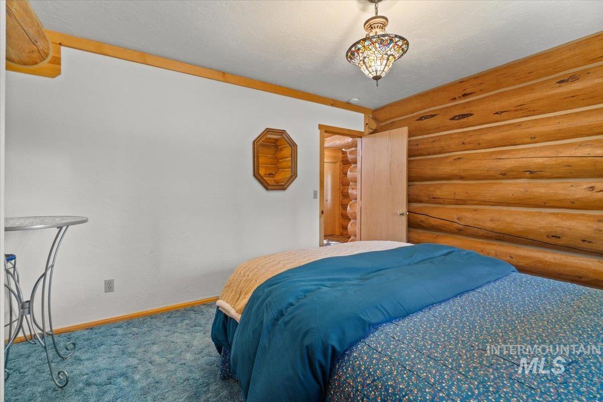3725 Rim Road New Meadows, ID 83654 - Photo 22 of 50 Carpeted bedroom with rustic walls and a textured ceiling