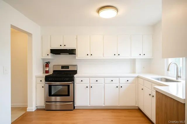 a kitchen with granite countertop white cabinets and stainless steel appliances
