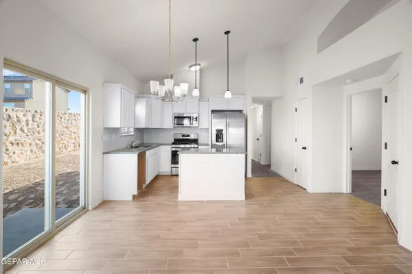 a kitchen with stainless steel appliances granite countertop a refrigerator a sink dishwasher a stove and white cabinets with wooden floor