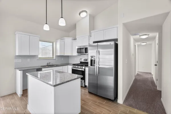 a kitchen with kitchen island a counter space a sink stainless steel appliances and cabinets