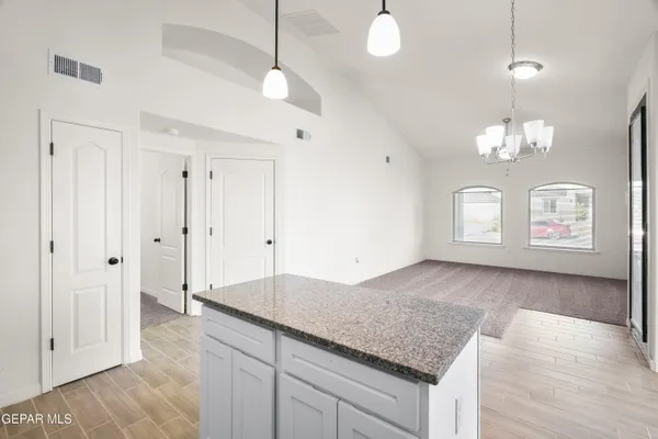 a large kitchen with granite countertop a sink dishwasher a stove and white cabinets with wooden floor