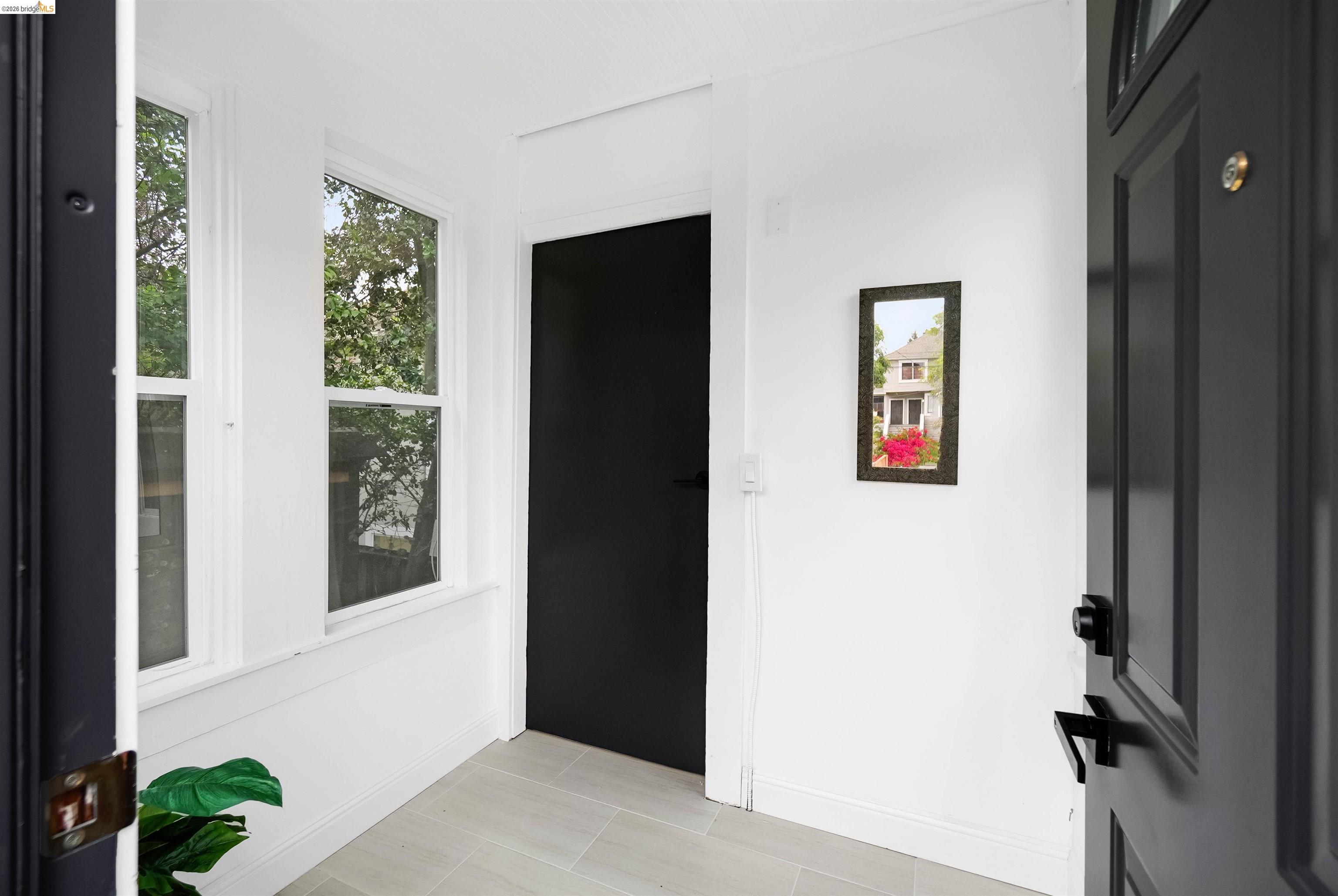 1812 Woolsey Street Berkeley, CA 94703 - Photo 4 of 48 Entryway featuring a paneled door with matte black hardware, light-toned tile flooring, and multiple windows