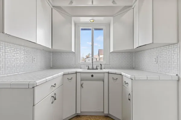 a kitchen with white cabinets and sink