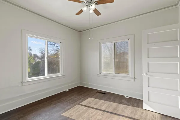 an empty room with wooden floor and windows