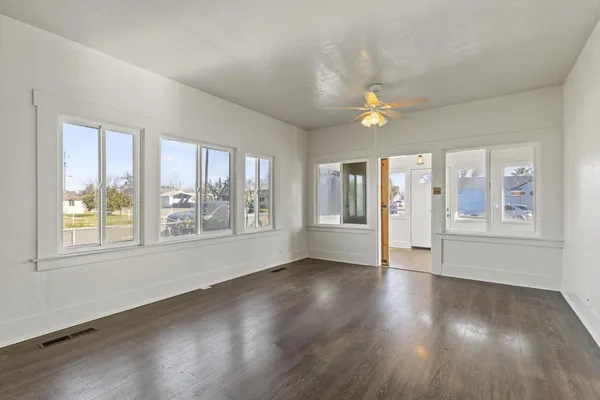 a view of an empty room with a window and wooden floor