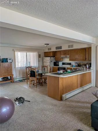 a kitchen with stainless steel appliances a stove a sink a oven and a dining table with wooden floor