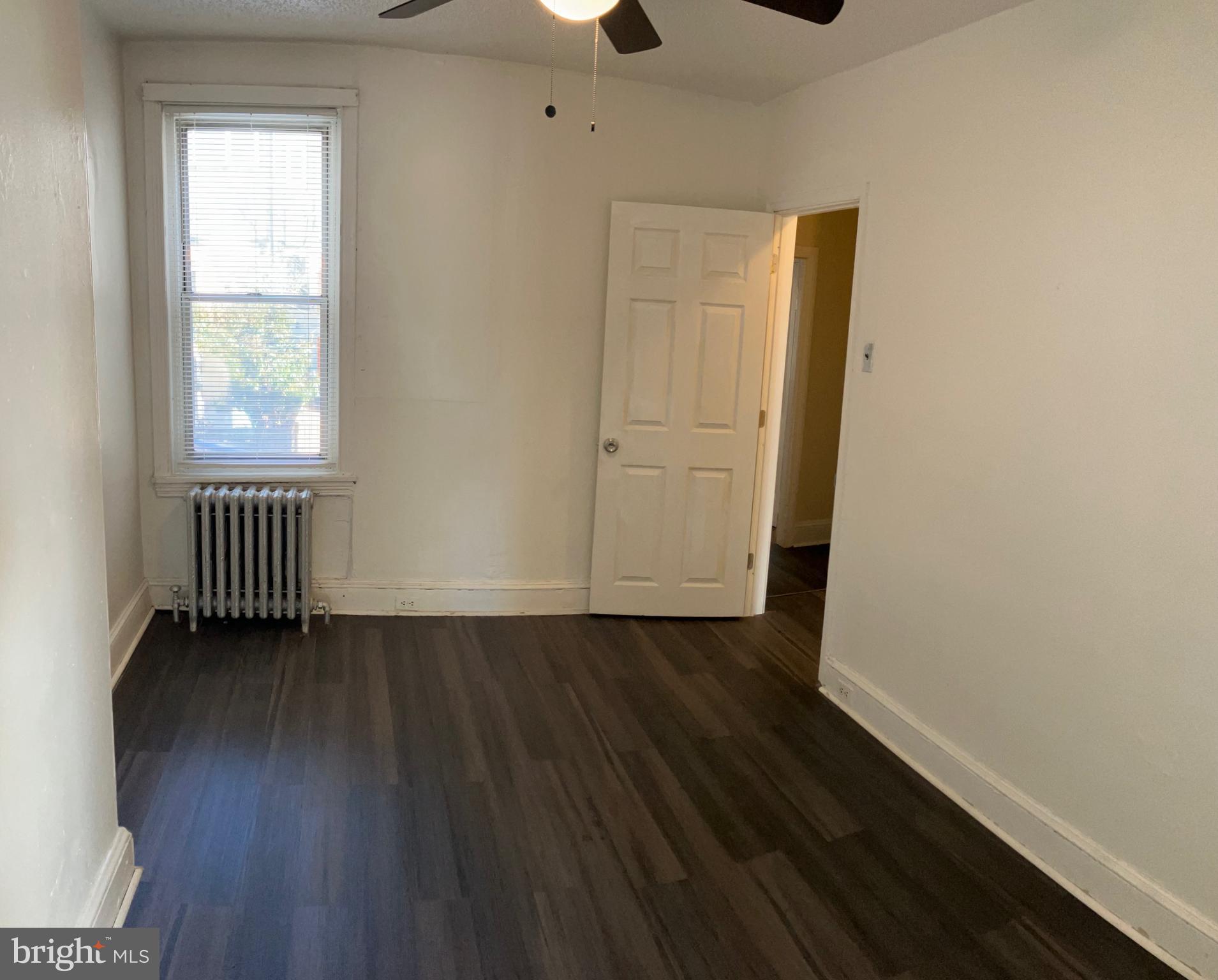 2215 Catharine Street, Unit 2 Philadelphia, PA 19146 - Photo 7 of 11 an empty room with wooden floor cabinet and windows