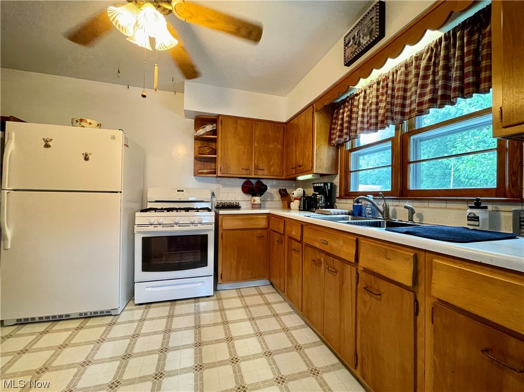66119 Highway 124 Reedsville, OH 45772 - Photo 17 of 29 Kitchen with backsplash, brown cabinets, light countertops, light tile floors, ceiling fan, and white appliances