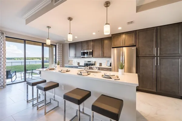 a kitchen with refrigerator a island and chairs