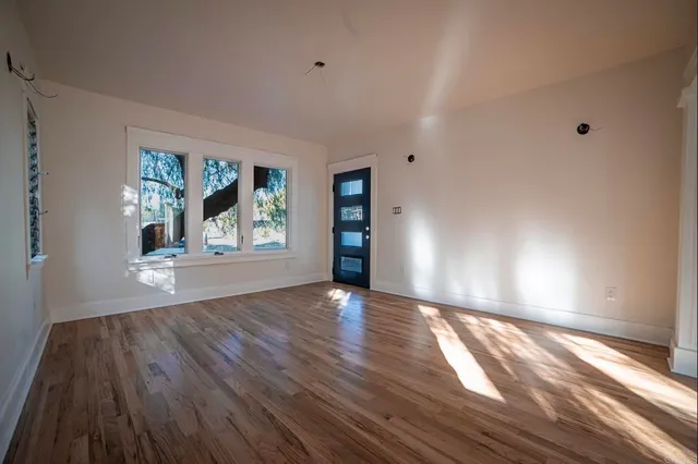a view of an empty room with wooden floor and a window