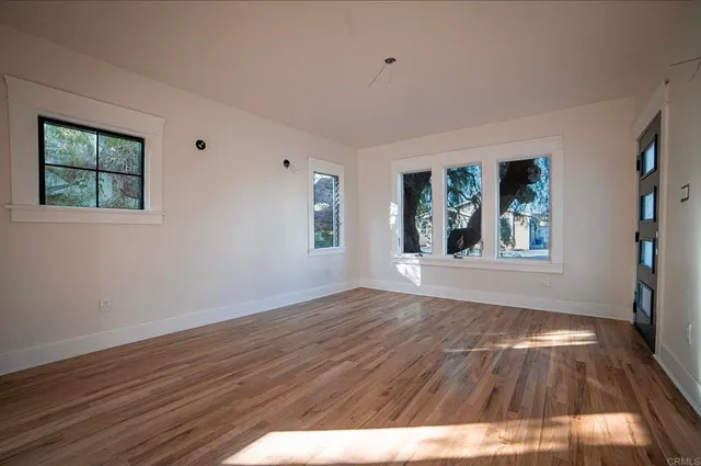 a view of an empty room with wooden floor and a window