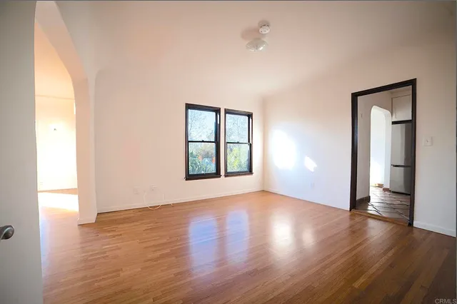 an empty room with wooden floor and windows