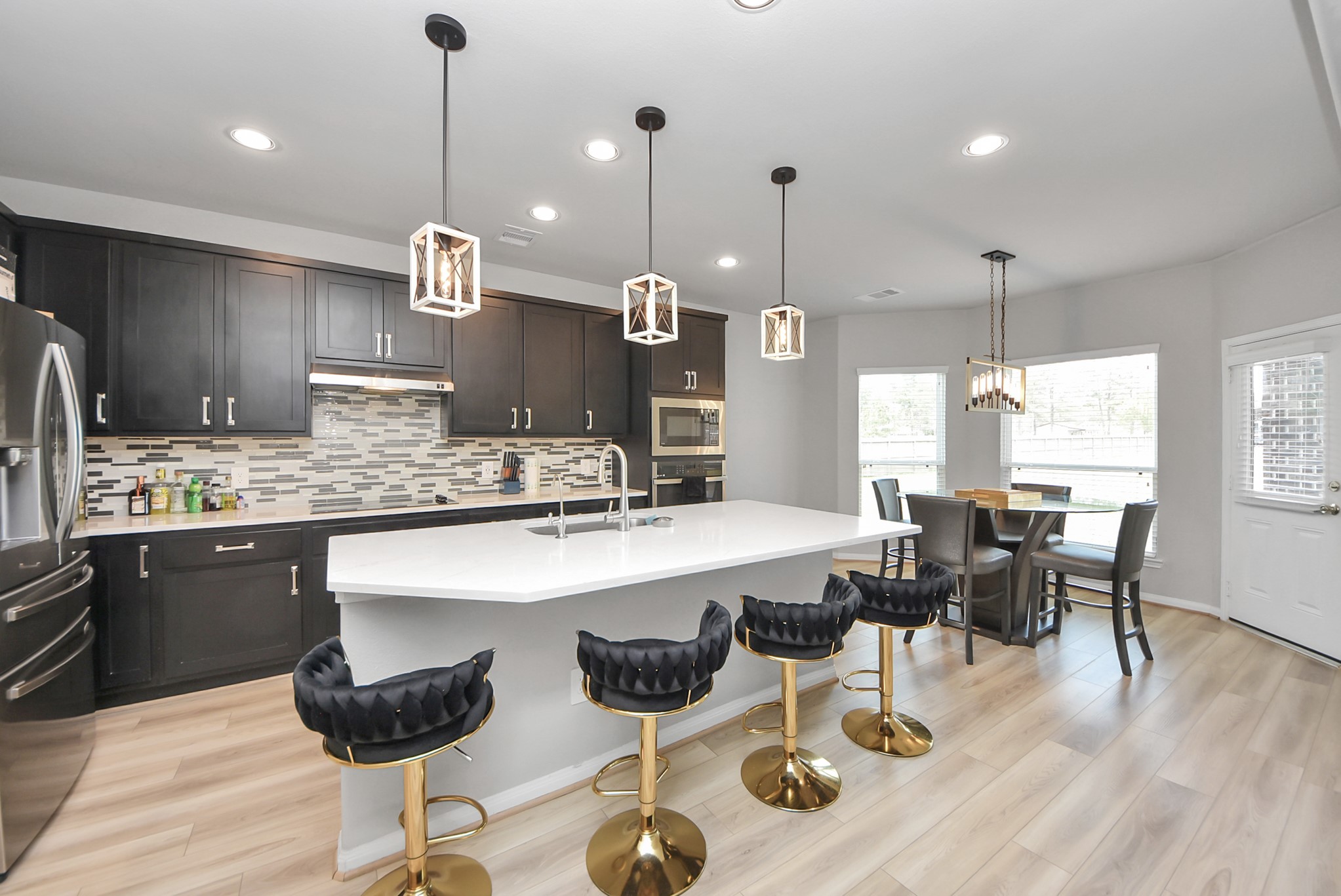 16735 Rockwall Street Conroe, TX 77303 - Photo 7 of 37 a kitchen with stainless steel appliances kitchen island granite countertop a sink a stove a dining table chairs and view living room
