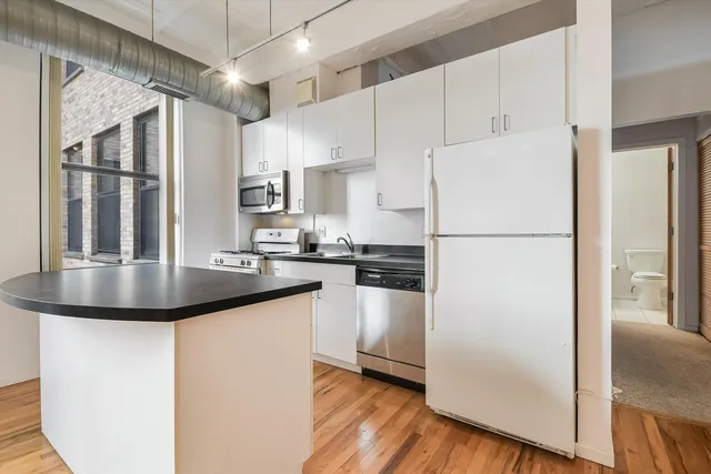 a kitchen with refrigerator a sink and white cabinets