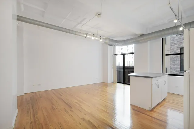 a kitchen with granite countertop a refrigerator and wooden floor