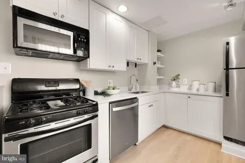 a kitchen with cabinets stainless steel appliances and wooden floor